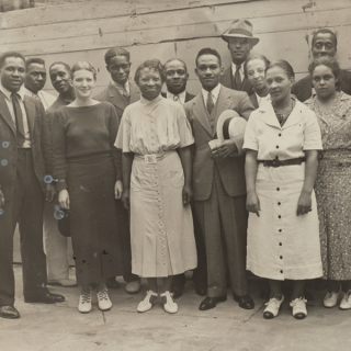 A group photo of Black visual artists against a tall wooden fence