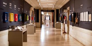 photograph of gallery corridor with colorful frames on wall and cases on the floor