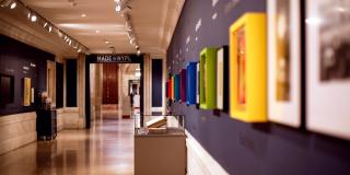 photograph of gallery corridor with colorful frames on wall and cases on the floor