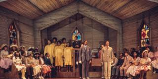 Color photo of people singing on stage in a church.