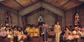 Color photo of people singing on stage in a church.