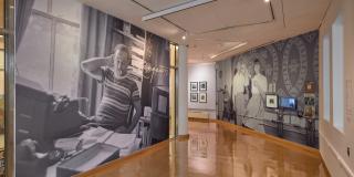 Installation view of gallery walls with a floor to ceiling black and white photo of Langston Hughes and a distant wall with a floor to ceiling black and white image of two people dancing