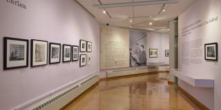 Installation view of gallery walls with black frame photos dotting the left wall