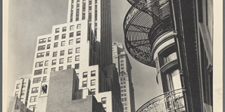 Black-and-white photograph taken at upward angle of a skyscraper at left, with curved, iron fire escapes of an older building framing the composition at right