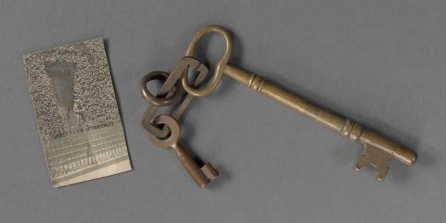 Photo of a small black-and-white newspaper clipping next to a set of large bronze keys.