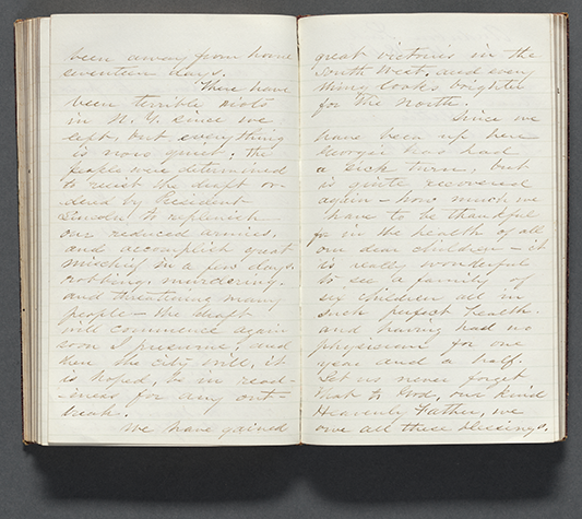 Photograph of an open diary, with a two-page spread featuring lined paper with cursive script writing