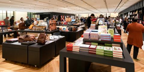 Groups of people in a large space with dark wooden shelves filled with books, tote bags, and accessories.