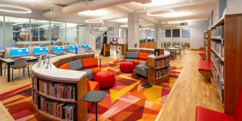 Interior of Melrose Teen Center with colorful seating, a rug, bookshelves, and computers.